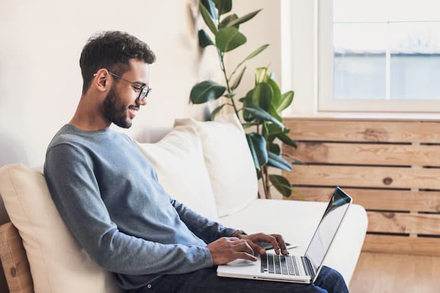 man using laptop on white couch